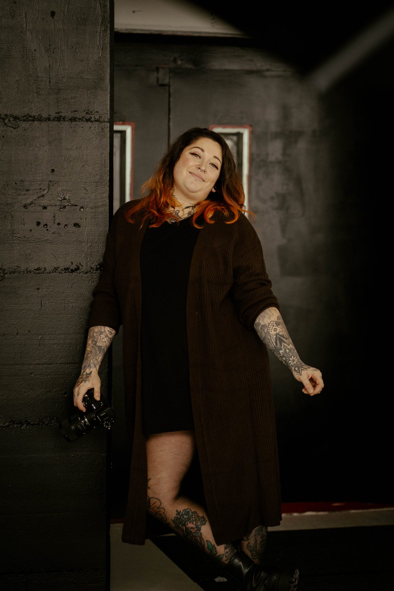 Lena - Fotografin aus der Pellenz - lehnt mit ihrer Kamera in der Hand an eine Wand