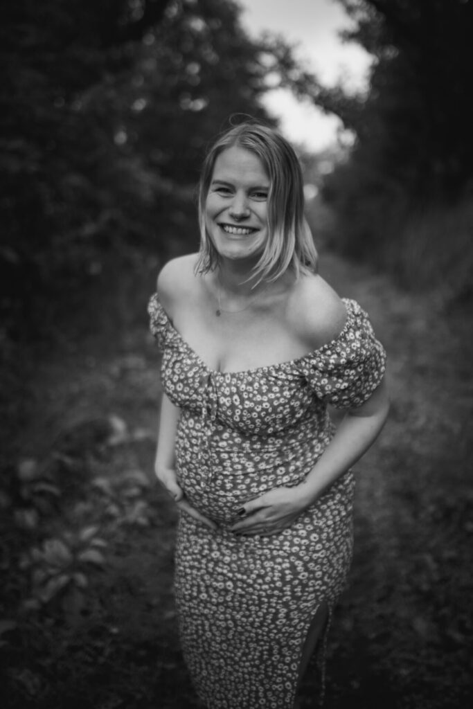 Babybauchshooting mit schwangerer Frau im Kleid an einem Waldrand in der Pellenz